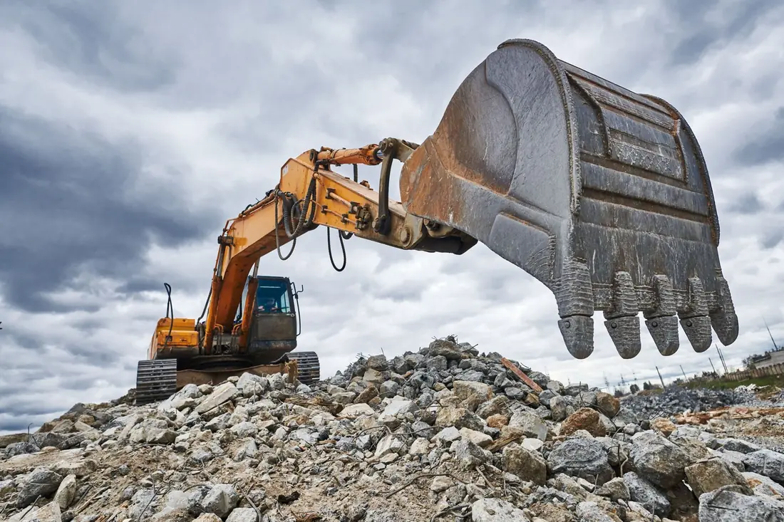 Excavator bucket over a rocky demolition site