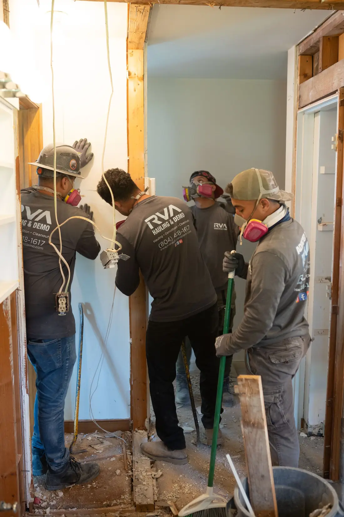 Workers removing a damaged interior wall in a doorway under renovation