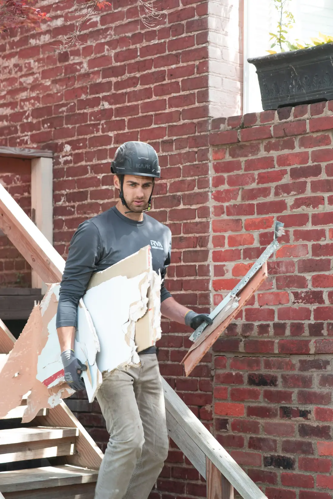 Worker carrying a large panel out of a commercial space under demolition